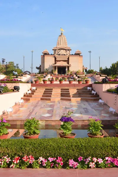 The grand entrance and lush gardens of a Beawar temple, inviting visitors on a peaceful retreat from Abu Road.