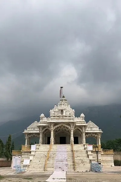 A majestic white Jain temple against the backdrop of lush green hills in Sirohi, a spiritual site on the Abu Road taxi tour.